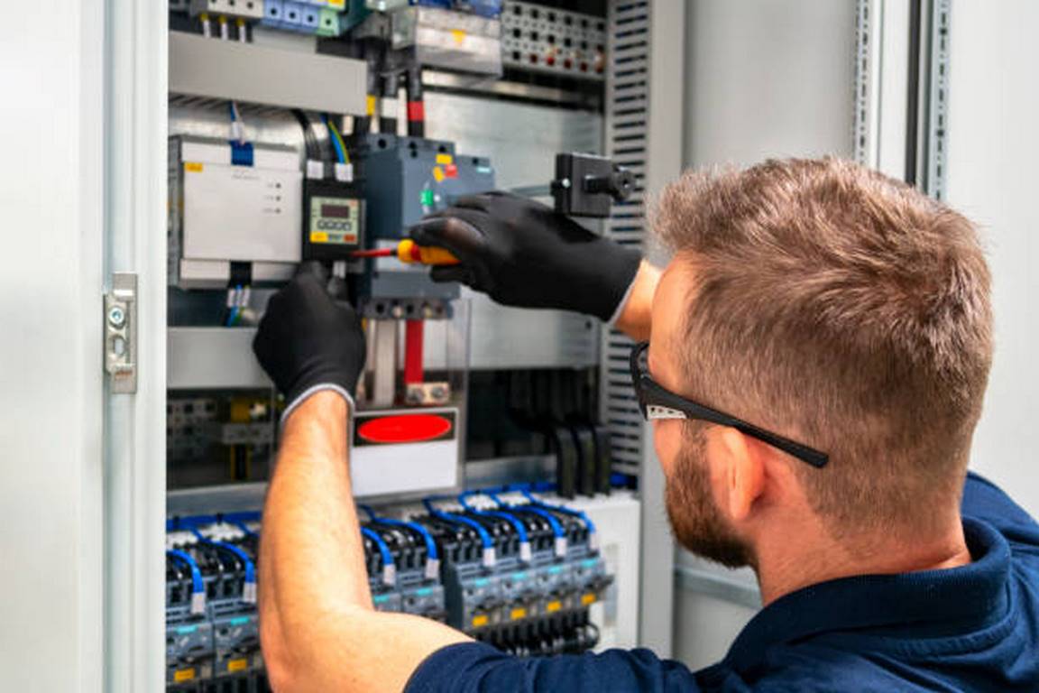 Photo of an electrician working at distribuition board.